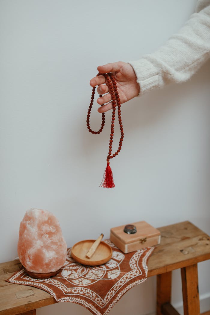 hero-img A serene setup featuring a beaded necklace, pink salt lamp, and sacred objects for meditation.